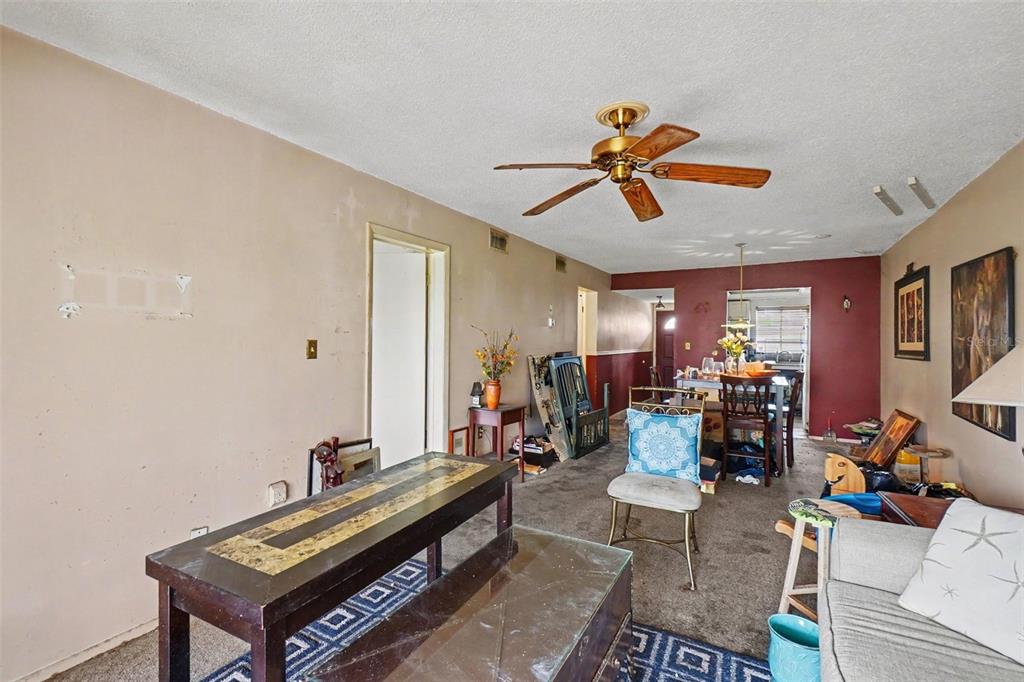 A living room with beige walls, a ceiling fan, and a dining area in the back — 4009 LAKE BAYSHORE DRIVE UNIT 105, BRADENTON, FL