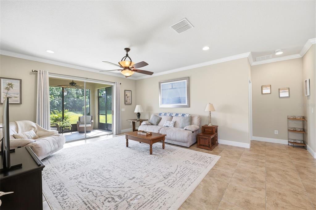 A living room features tile flooring, a ceiling fan, a sofa, and sliding glass doors — 1707 TRILLIUM BOULEVARD, BROOKSVILLE, FL