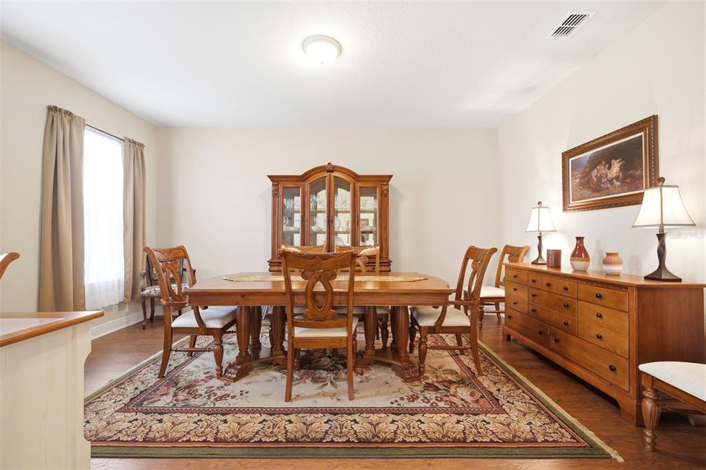 A dining room features a wooden table, chairs, a hutch, and a sideboard on a rug — 1707 TRILLIUM BOULEVARD, BROOKSVILLE, FL