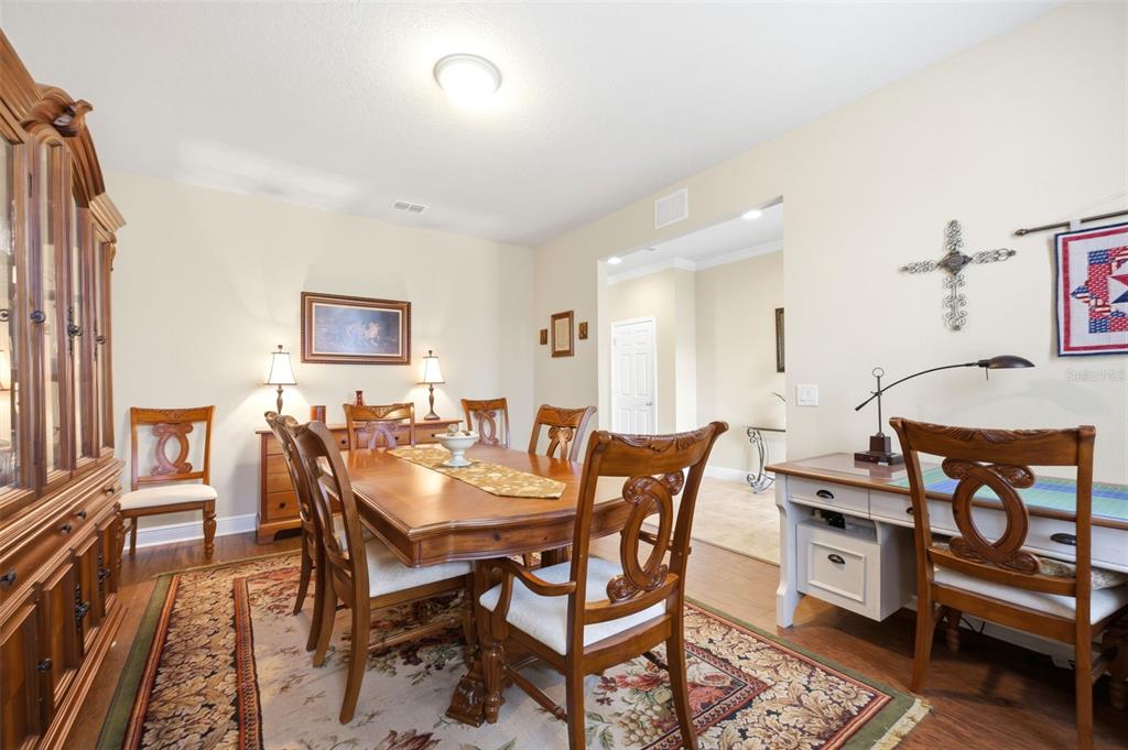 A dining room features a wooden table, chairs, a hutch, and a desk area — 1707 TRILLIUM BOULEVARD, BROOKSVILLE, FL