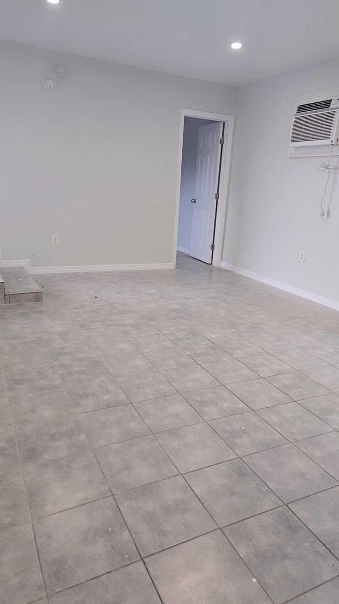 An empty room with gray tile flooring, white walls, a doorway, and a window air conditioner — 621 NW 5th Avenue Unit 4, Pompano Beach FL 33060, POMPANO BEACH, FL
