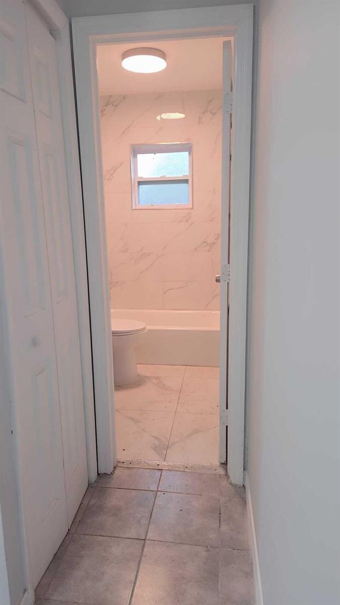 A view through a doorway into a bathroom with marble-look tile and a bathtub — 621 NW 5th Avenue Unit 4, Pompano Beach FL 33060, POMPANO BEACH, FL