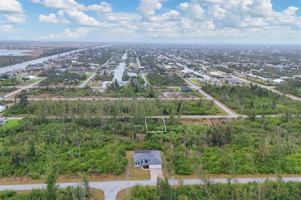 An aerial view shows a vacant, rectangular lot outlined in white amidst dense vegetation — 10558 HILLWOOD DRIVE, PORT CHARLOTTE, FL