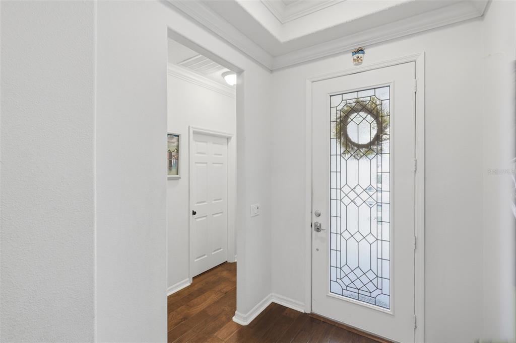 A white front door with a decorative glass insert opens into a foyer with wood flooring — 9552 PICCADILLY SKY WAY, ORLANDO, FL