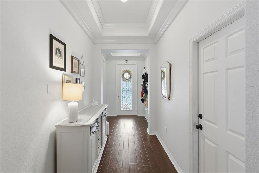 A bright entryway features white walls, dark wood flooring, a console table, and a front door — 9552 PICCADILLY SKY WAY, ORLANDO, FL