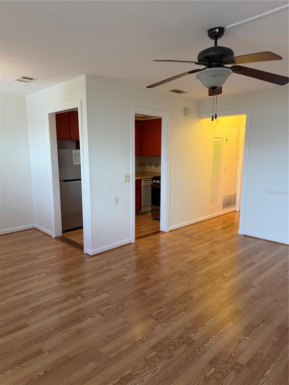 A living area with hardwood floors leads to a kitchen and a hallway — 5850 18TH STREET N UNIT 16, ST PETERSBURG, FL