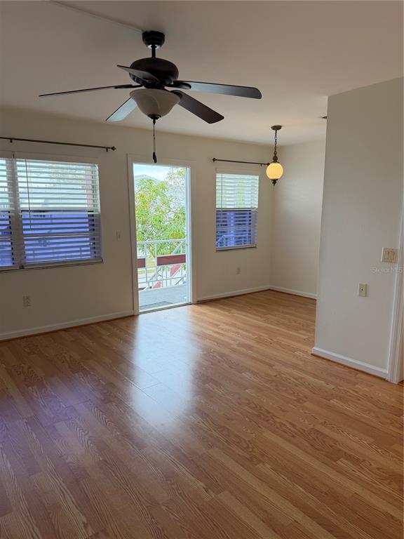 An empty room with hardwood floors, a ceiling fan, and a door leading to a balcony — 5850 18TH STREET N UNIT 16, ST PETERSBURG, FL
