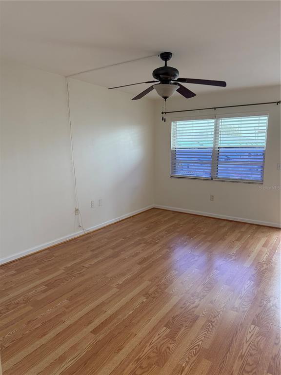 An empty room features light wood-look flooring, white walls, a ceiling fan, and a window — 5850 18TH STREET N UNIT 16, ST PETERSBURG, FL