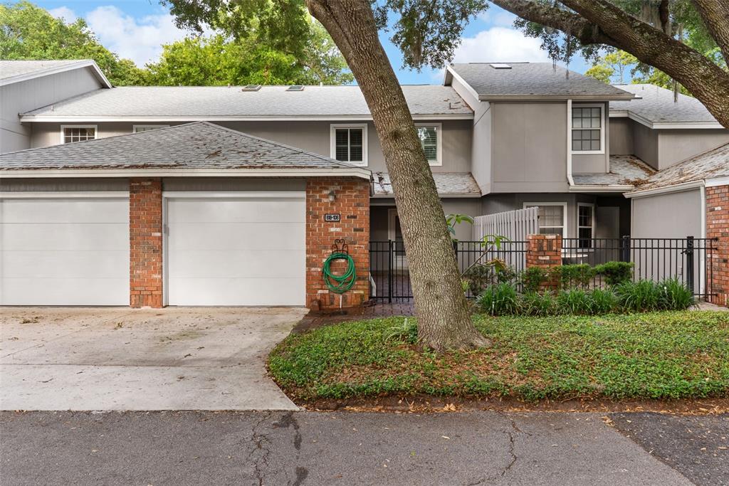 A two-story townhouse with a gray exterior, brick accents, a two-car garage, and a tree — 618 MAPLE OAK CIRCLE UNIT 108, ALTAMONTE SPRINGS, FL