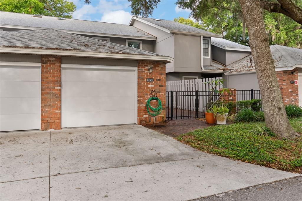 A residential exterior view showing a garage, brick facade, and a fenced patio area — 618 MAPLE OAK CIRCLE UNIT 108, ALTAMONTE SPRINGS, FL