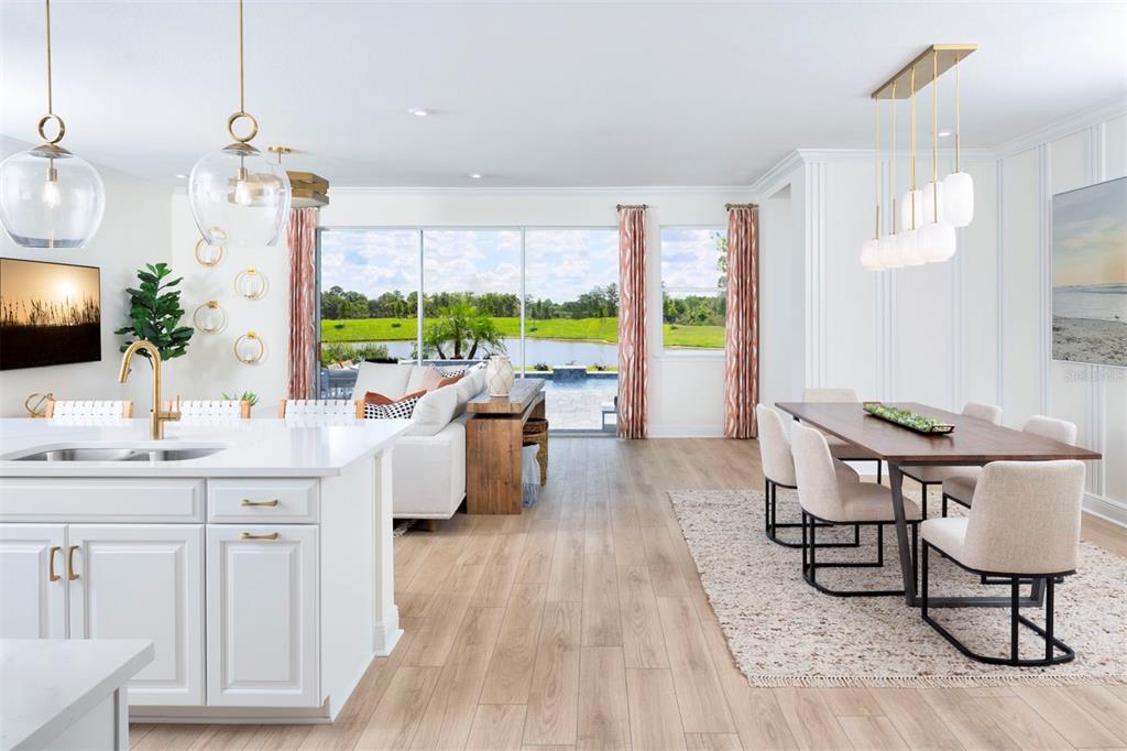 A bright open-concept kitchen, dining area, and living room overlook a backyard pool and lake — 11811 STARBRIGHT PATH, VENICE, FL