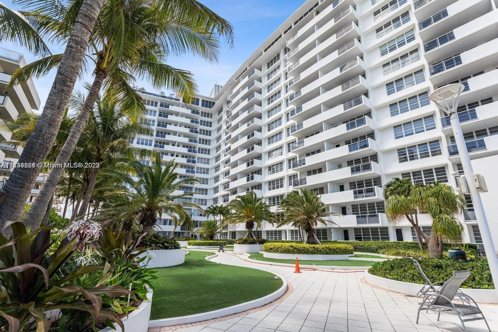 A multi-story white apartment building overlooks a landscaped courtyard with palm trees and walkways — 100 Lincoln Rd # 1612, Miami Beach FL 33139, MIAMI BEACH, FL