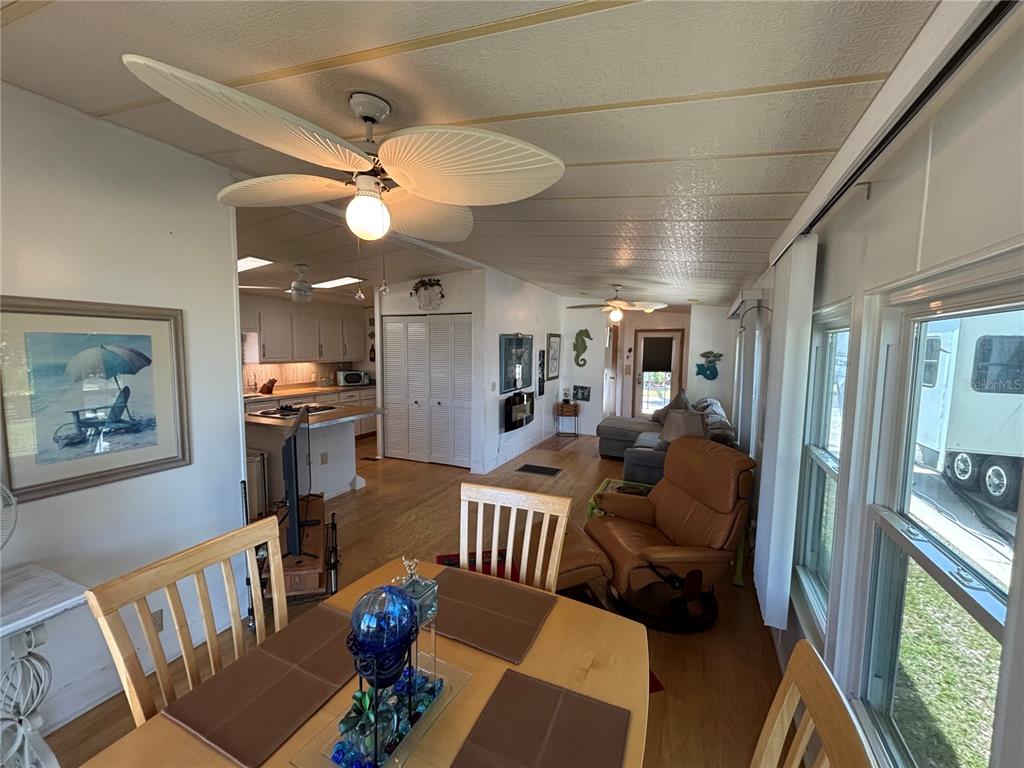 An open-concept living and dining area features wood flooring, a ceiling fan, and a kitchen — 9000 US HIGHWAY 192 UNIT 894, CLERMONT, FL