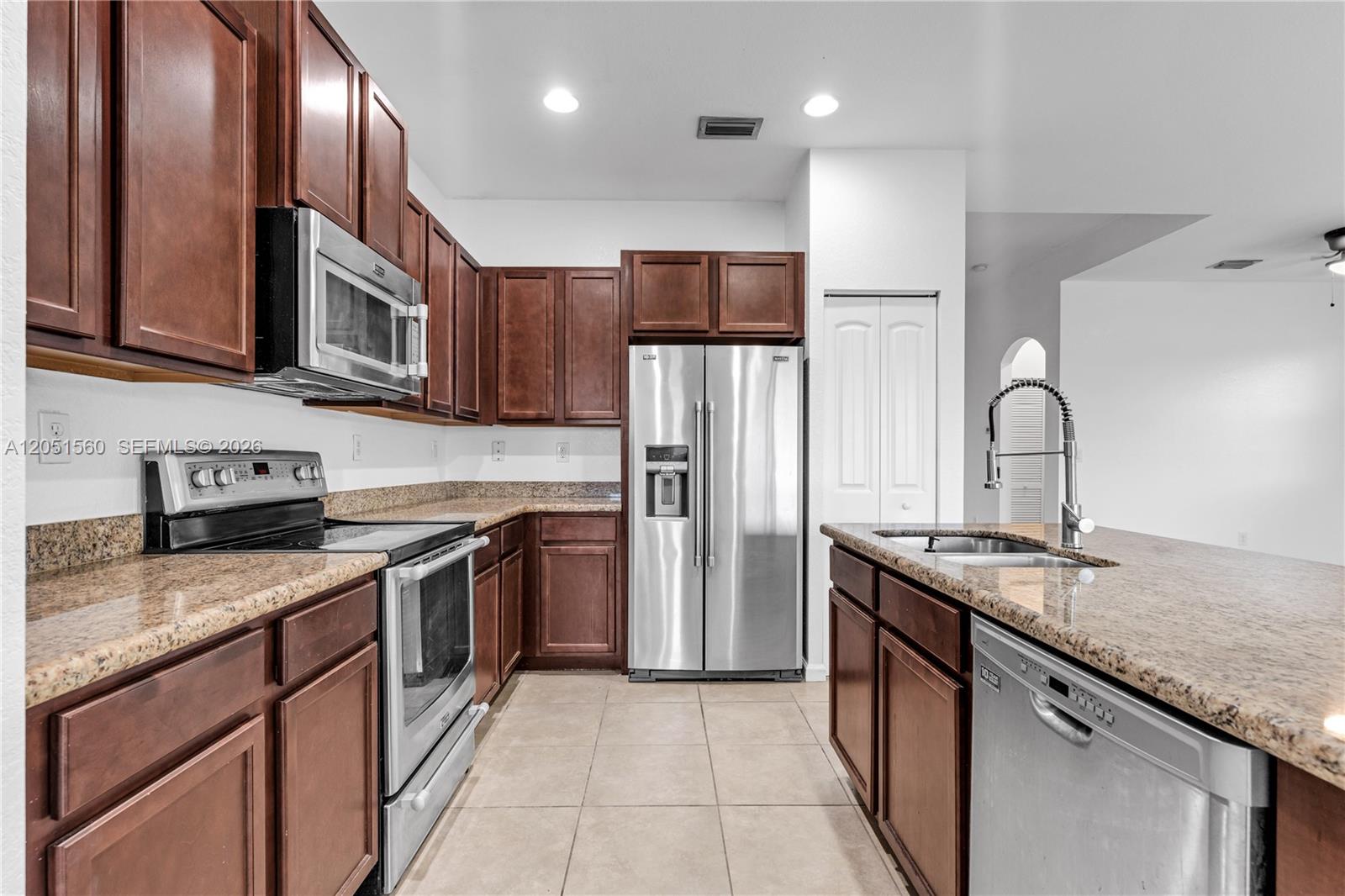 A kitchen features dark wood cabinets, granite countertops, and stainless steel appliances — 28381 SW 128th Pl, Homestead FL 33033, HOMESTEAD, FL