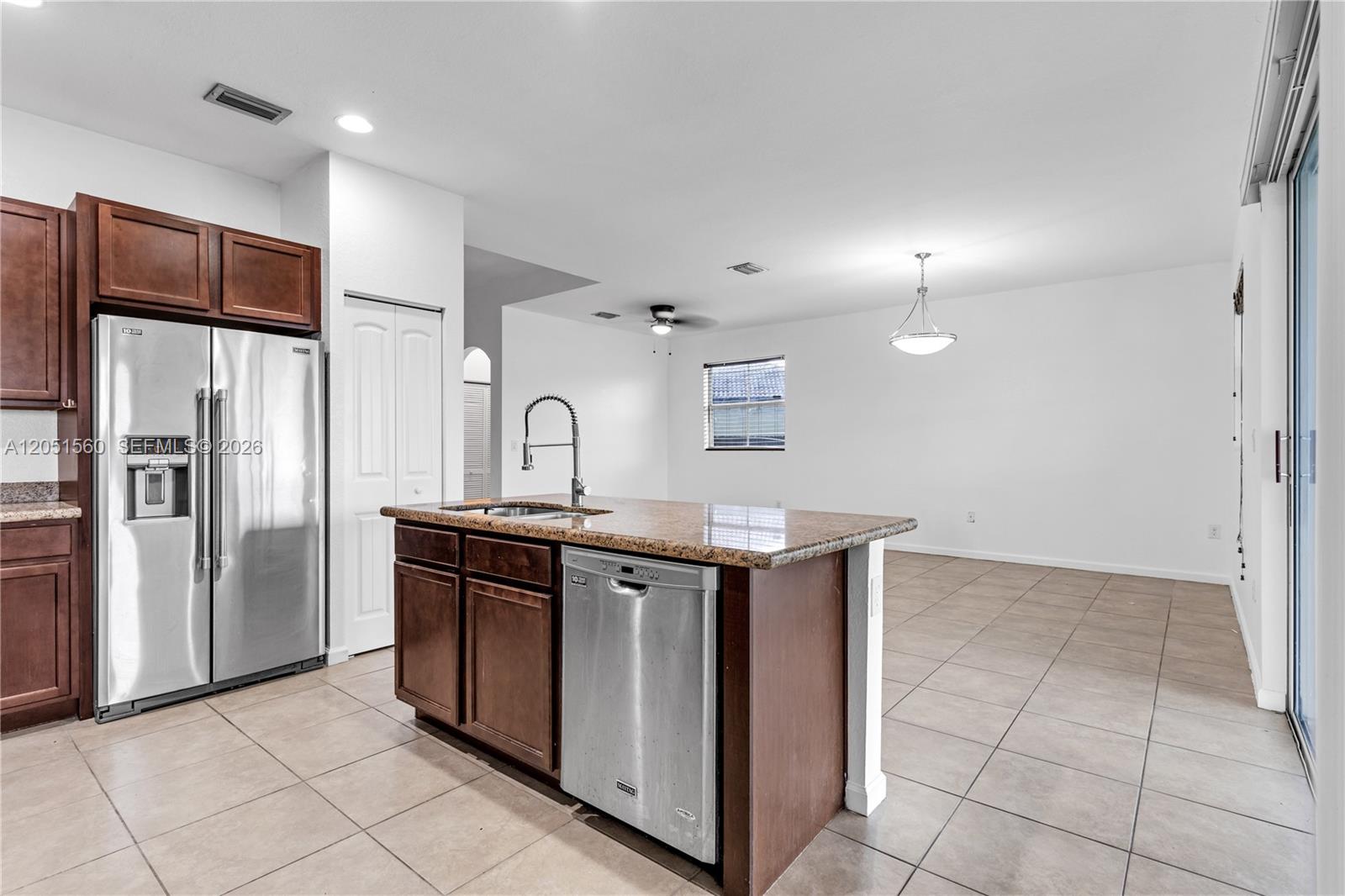 A kitchen features dark wood cabinets, granite countertops, stainless steel appliances, and tile flooring — 28381 SW 128th Pl, Homestead FL 33033, HOMESTEAD, FL