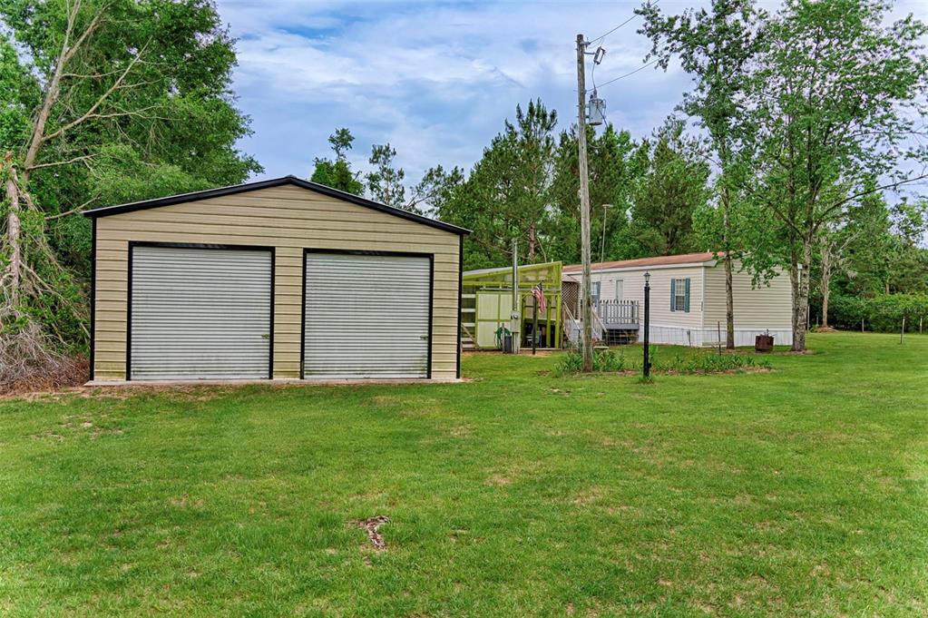 A metal two-car garage stands next to a mobile home on a grassy lot — 7776 SE 113TH COURT, JASPER, FL