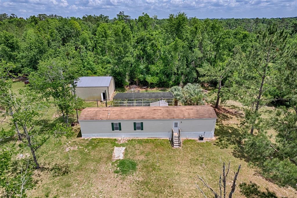 An aerial view shows a manufactured home, a detached metal garage, and a screened enclosure — 7776 SE 113TH COURT, JASPER, FL