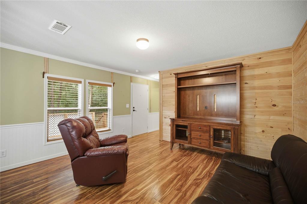 A living room features wood-paneled walls, a brown leather recliner, and a wooden entertainment center — 11821 SE 82ND STREET, MORRISTON, FL
