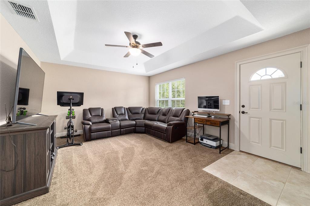 A living room features a brown sectional sofa, a television, a desk, and a ceiling fan — 15792 SW 55TH AVENUE ROAD, OCALA, FL