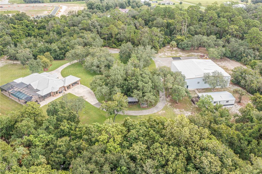 An aerial view shows a house with a pool enclosure, a large workshop, and trees — 1617 HORSESHOE CREEK ROAD, DAVENPORT, FL