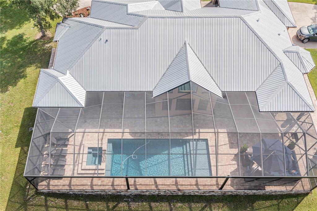 An aerial view shows a house with a metal roof and a screened-in pool enclosure — 1617 HORSESHOE CREEK ROAD, DAVENPORT, FL