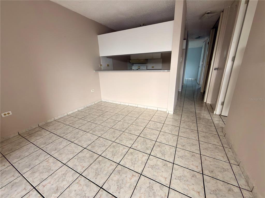 A room with light-colored tile flooring and a pass-through opening to a kitchen — 2 CALLE UNIT 227, TRUJILLO ALTO, PR