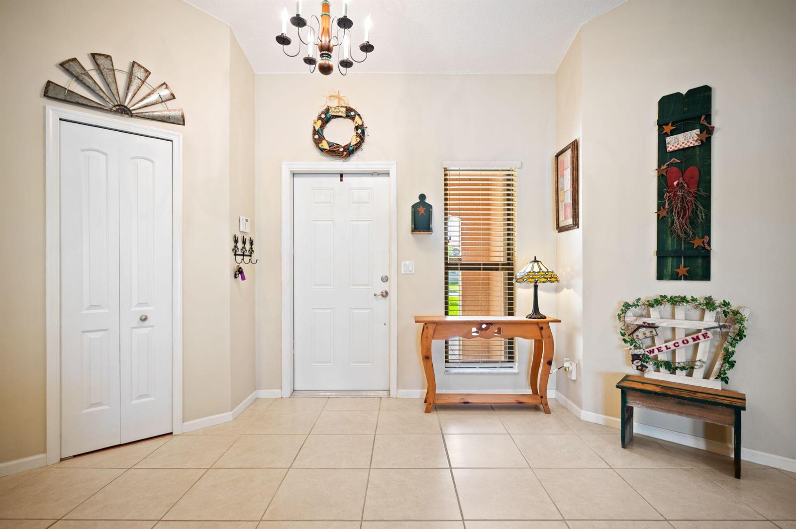 A tiled entryway features a white front door, a wooden console table, and decorative wall hangings — 5531 Hawkes Bluff Avenue, Davie FL 33331, DAVIE, FL