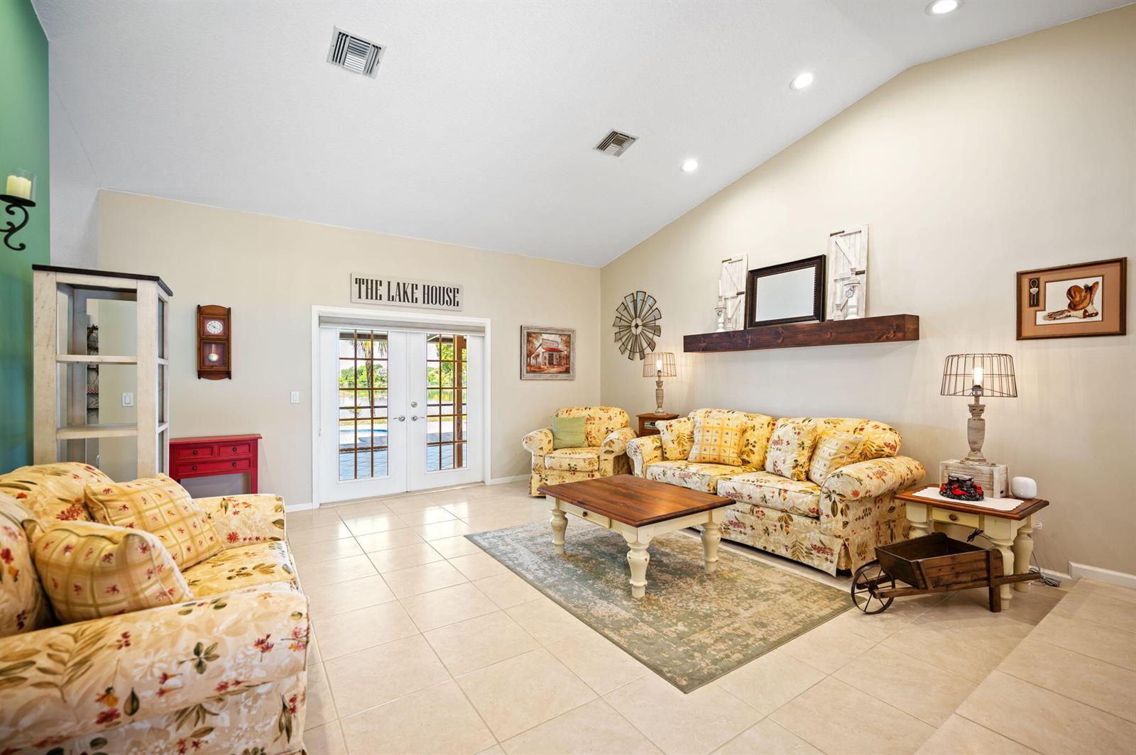 A living room with floral sofas, a wooden coffee table, and French doors to outside — 5531 Hawkes Bluff Avenue, Davie FL 33331, DAVIE, FL