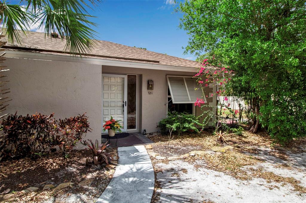 A single-story house exterior features a white front door, a shuttered window, and landscaping — 721 N JEFFERSON AVENUE UNIT 721, SARASOTA, FL
