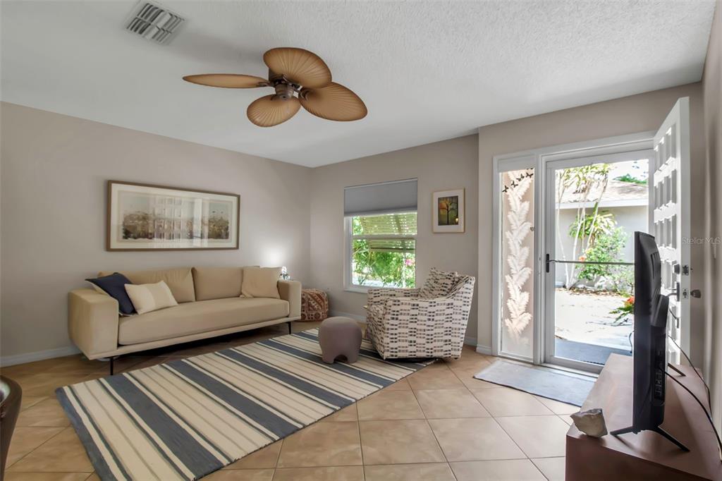 A living room with a beige sofa, patterned armchair, striped rug, and a glass door — 721 N JEFFERSON AVENUE UNIT 721, SARASOTA, FL
