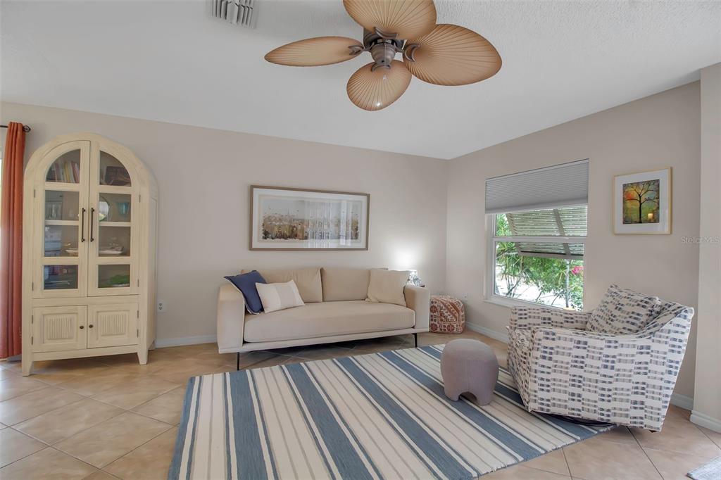 A living room features a beige sofa, patterned armchair, striped rug, and a ceiling fan — 721 N JEFFERSON AVENUE UNIT 721, SARASOTA, FL