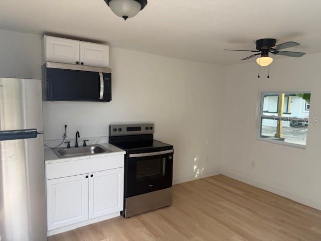 A small kitchen features white cabinets, stainless steel appliances, and light wood-look flooring — 4605 N HUBERT AVENUE UNIT 21, TAMPA, FL