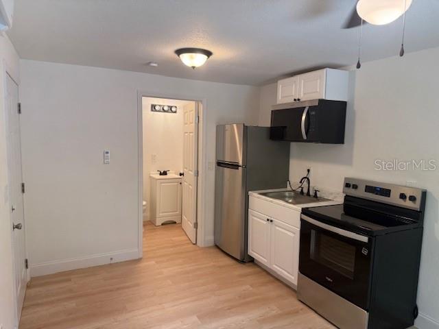 A small kitchen features stainless steel appliances, white cabinets, and light wood-look flooring — 4605 N HUBERT AVENUE UNIT 21, TAMPA, FL