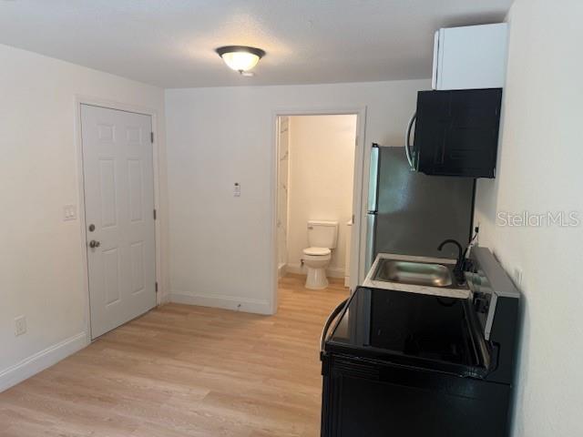 This studio apartment features light wood-look flooring, a small kitchenette, and an attached bathroom — 4605 N HUBERT AVENUE UNIT 21, TAMPA, FL