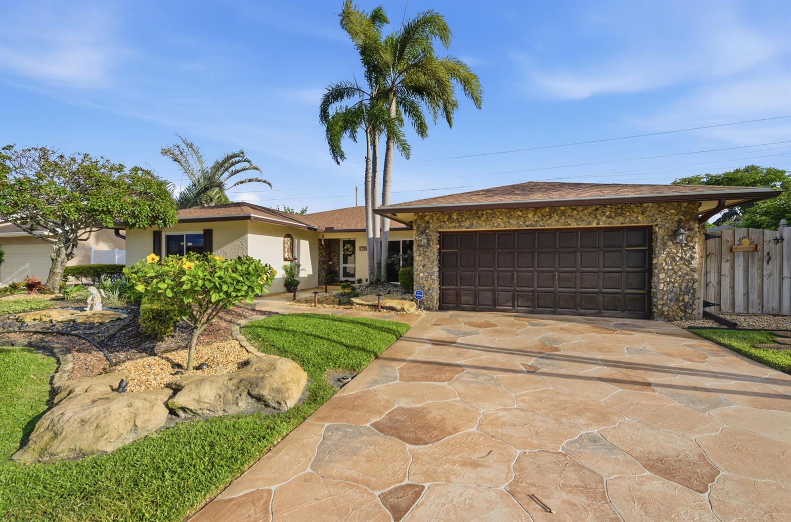 A single-story house with a stone-faced garage, palm trees, and a patterned concrete driveway — 4780 Brandywine Drive, Boca Raton FL 33487, BOCA RATON, FL