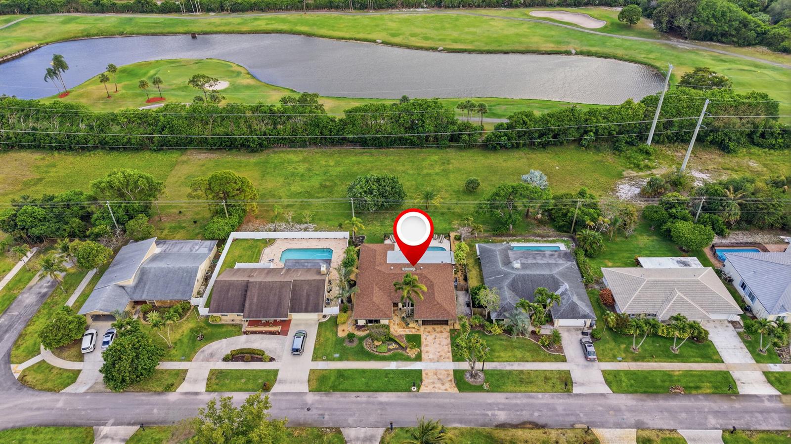 An aerial view shows a suburban house with a brown roof and pool near a lake — 4780 Brandywine Drive, Boca Raton FL 33487, BOCA RATON, FL