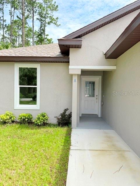 An exterior view of a tan house with a white front door and a window — 29 SLUMBER PATH UNIT A, PALM COAST, FL