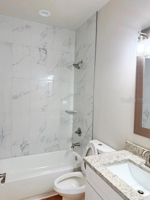 A bathroom features a white bathtub with marble-look tile walls and a granite-topped vanity — 29 SLUMBER PATH UNIT A, PALM COAST, FL