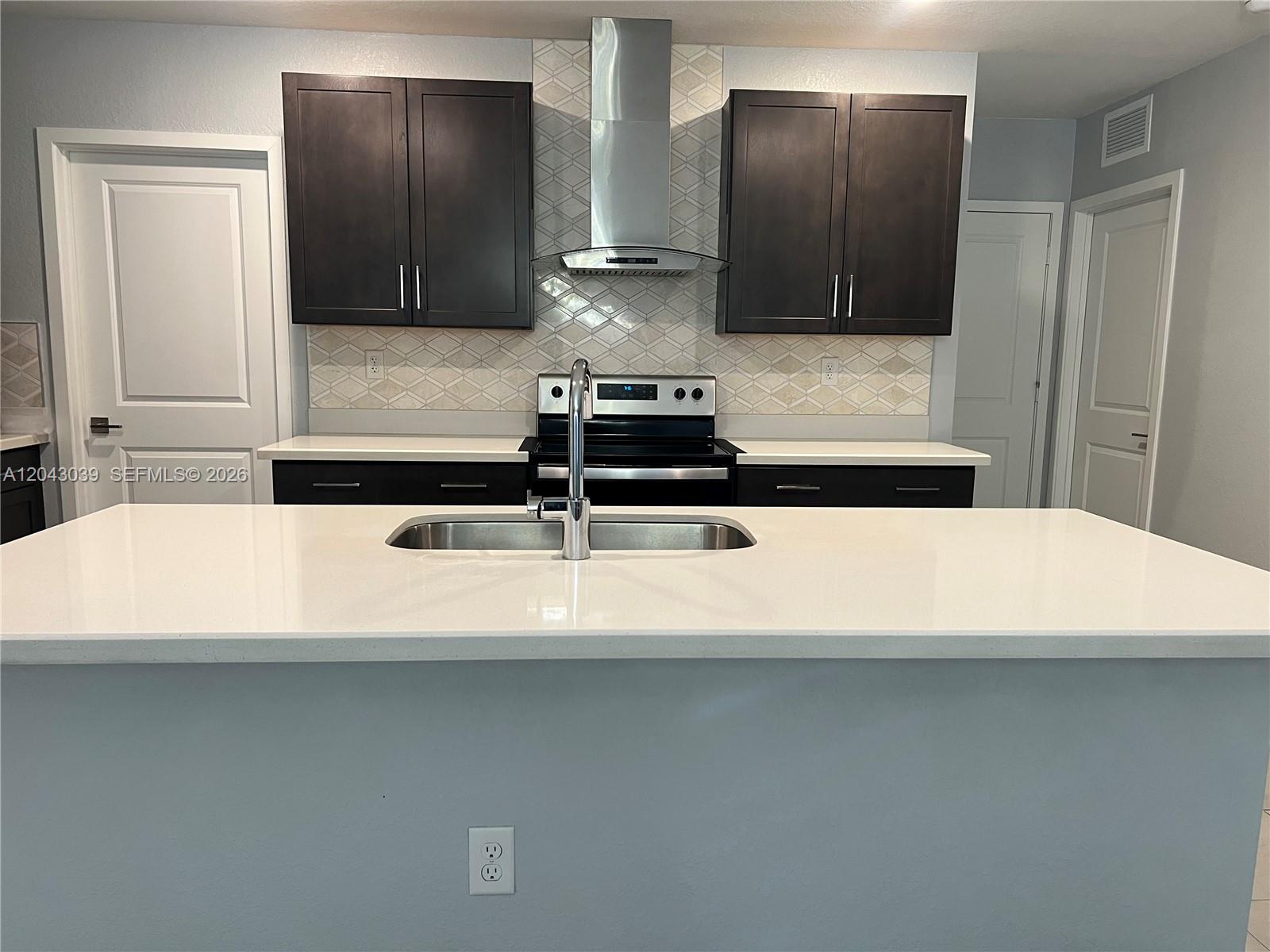 A kitchen features dark cabinets, white countertops, a stainless steel range, and a central island — 421 NE 6th Ct, Florida City FL 33034, FLORIDA CITY, FL