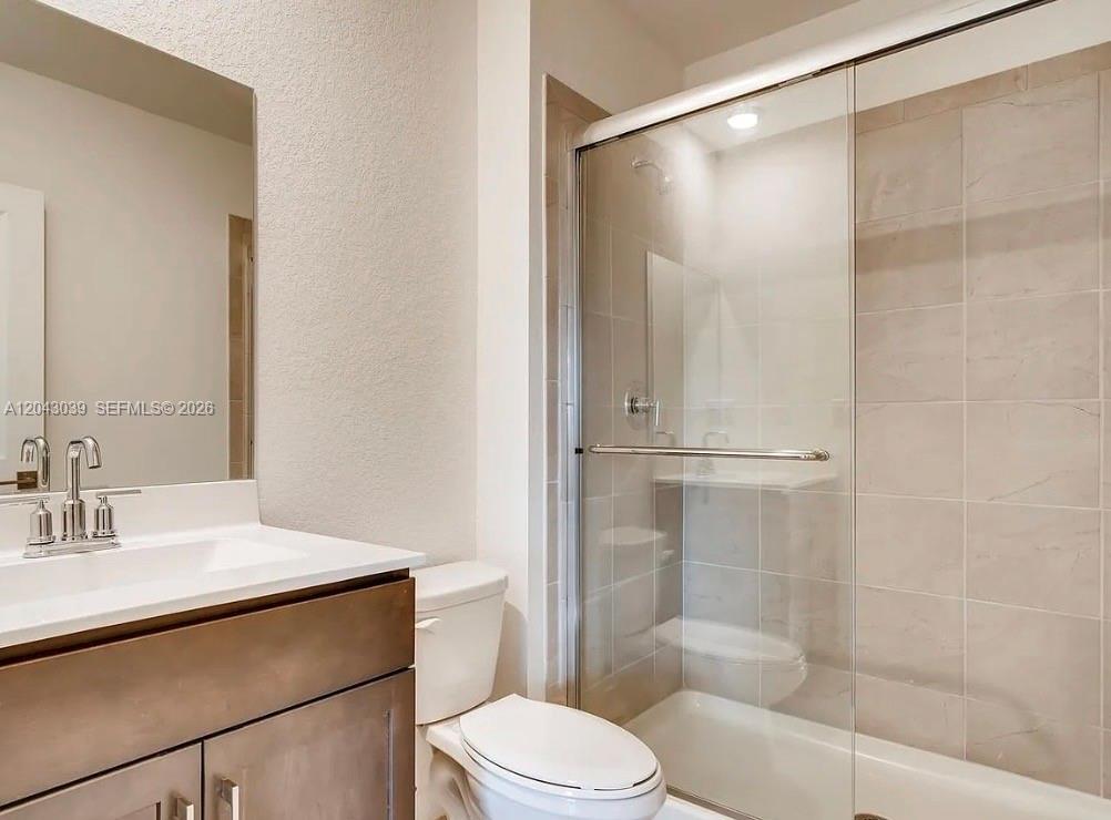 A bathroom features a vanity with a sink, a toilet, and a glass-enclosed shower — 421 NE 6th Ct, Florida City FL 33034, FLORIDA CITY, FL