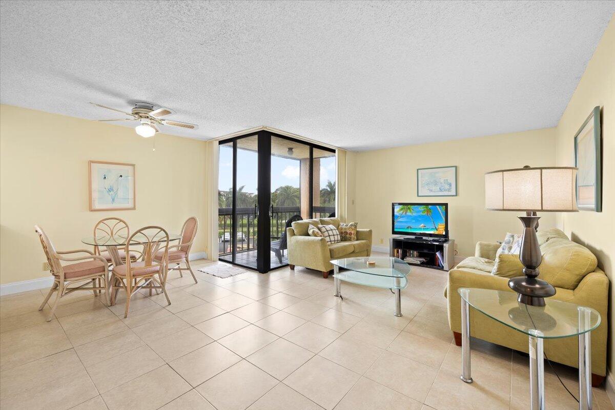 A living and dining area with tile floors, a glass table, and a glass-enclosed balcony — 2255 Lindell Boulevard # 4401, Delray Beach FL 33444, DELRAY BEACH, FL