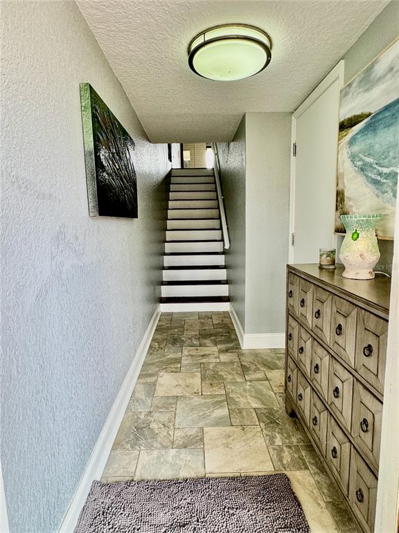 A tiled entryway features a staircase, a wooden dresser, and wall art — 513 HAVEN POINT DRIVE, TREASURE ISLAND, FL