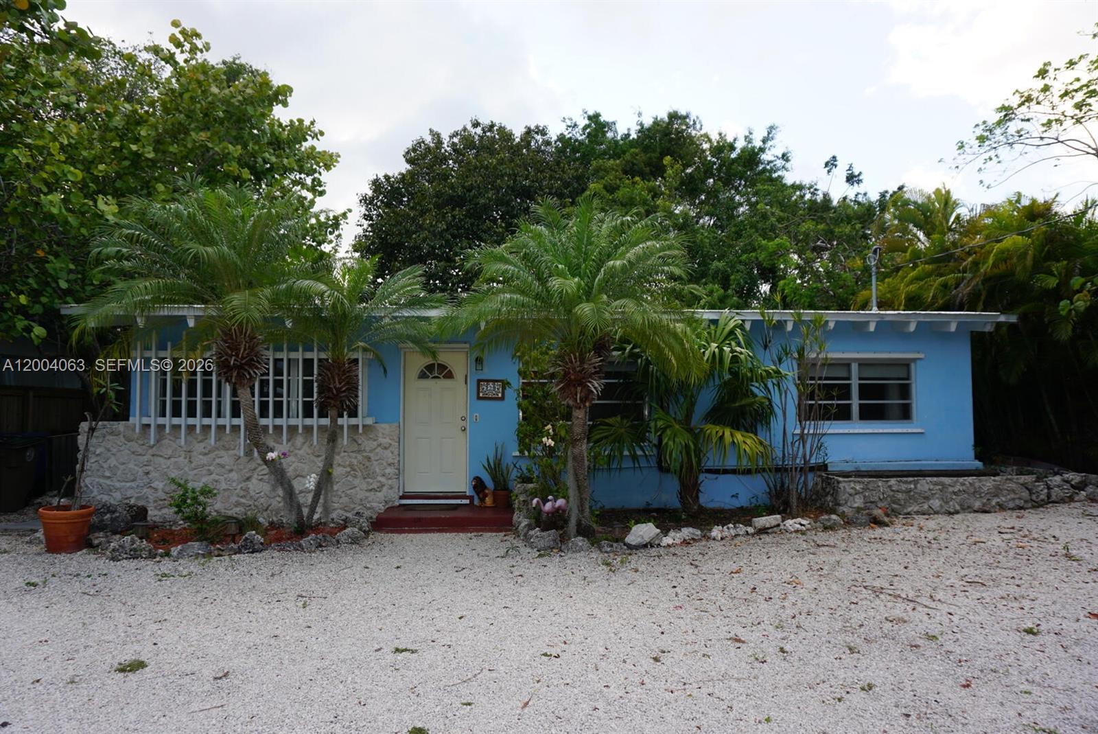 A single-story blue house with a stone facade, palm trees, and a gravel driveway — 229 2nd Rd, Key Largo FL 33037, KEY LARGO, FL
