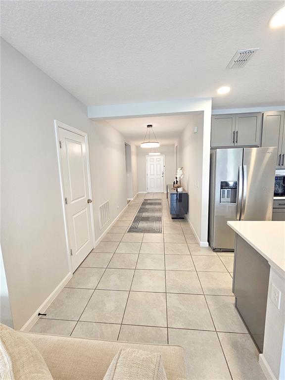 A tiled hallway leads from a kitchen area toward a white front door — 3775 KNOTTY PINE STREET, ST CLOUD, FL