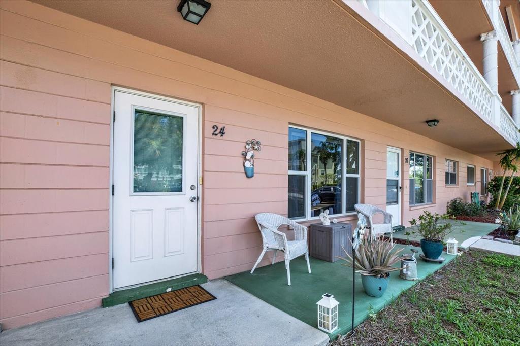 A pink exterior wall features a white front door labeled 24 and a small patio — 2458 COLUMBIA DRIVE UNIT 24, CLEARWATER, FL