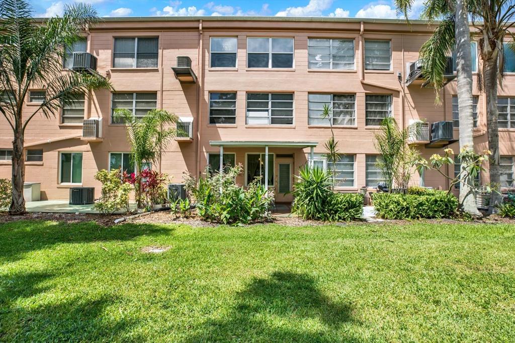 A three-story apartment building with a grassy lawn and landscaping in the foreground — 2458 COLUMBIA DRIVE UNIT 24, CLEARWATER, FL