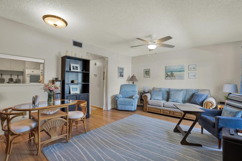 A living room with a dining area, featuring a sofa, armchairs, and wood-look flooring — 2458 COLUMBIA DRIVE UNIT 24, CLEARWATER, FL