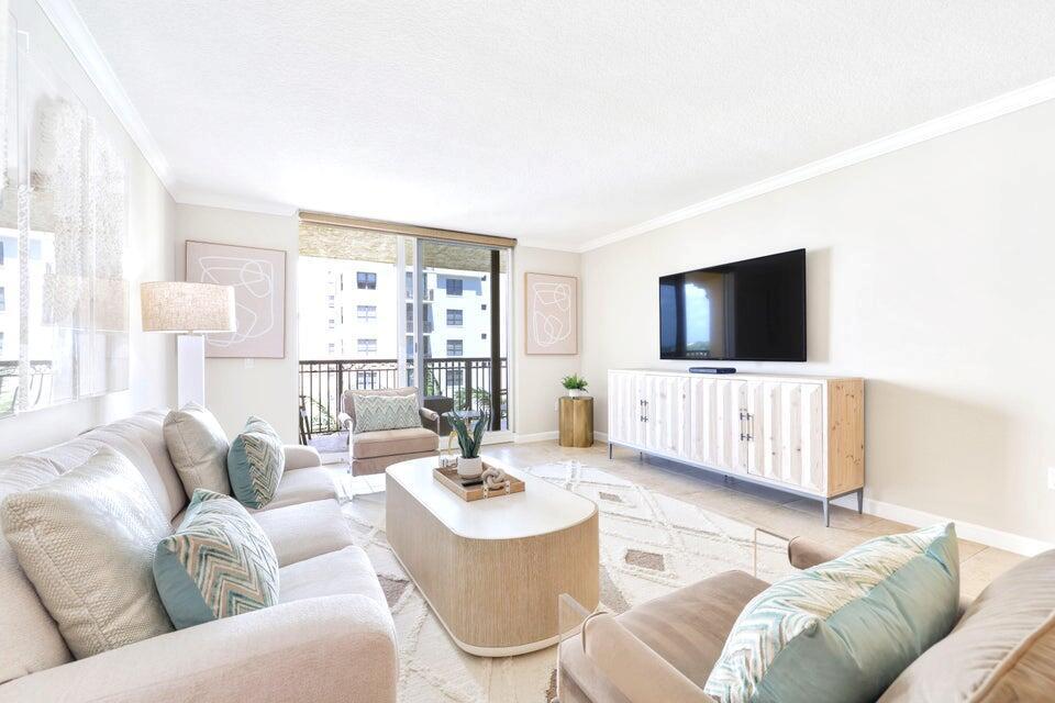 A bright living room features a beige sofa, patterned accent pillows, and a wooden media console — 101 Plaza Real S # 606, Boca Raton FL 33432, BOCA RATON, FL
