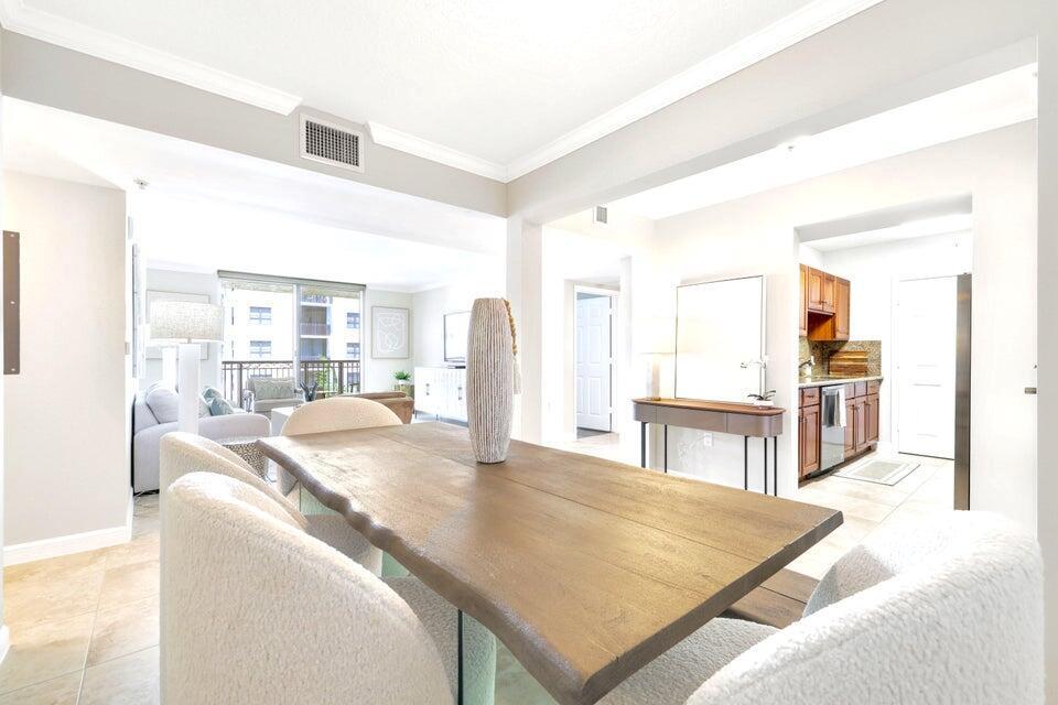 A dining area with a wooden table and chairs leads into a living room — 101 Plaza Real S # 606, Boca Raton FL 33432, BOCA RATON, FL