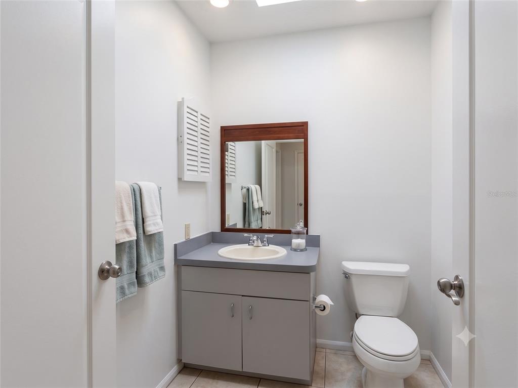 A small bathroom features a gray vanity, a wood-framed mirror, and a white toilet — 4975 DAVID AVENUE, SARASOTA, FL